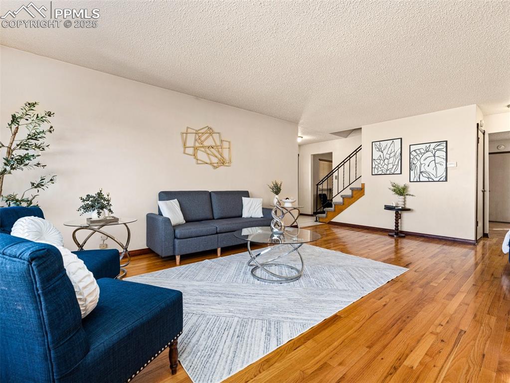 Image 3 of 38: Living room with stairway, wood finished floors, and a textured ceiling