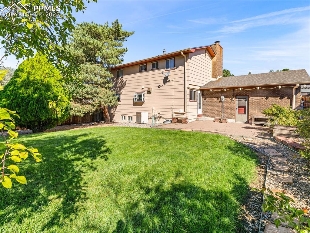 Image 35 of 38: Back of house with a patio, a chimney, and brick siding