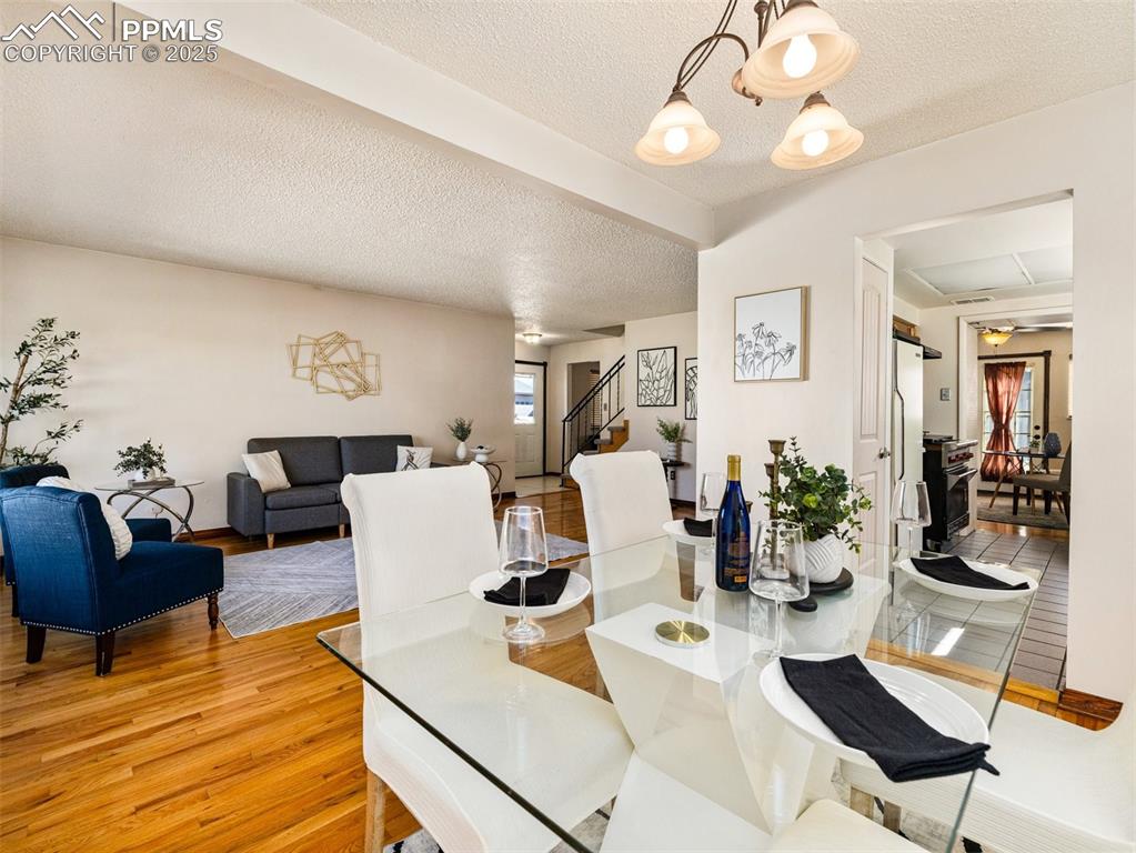 Image 5 of 38: Dining area with a textured ceiling, stairway, light wood-style floors, and