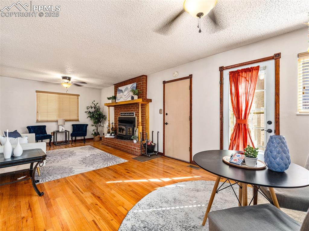 Image 8 of 38: Living room with a ceiling fan, a textured ceiling, and wood finished floor