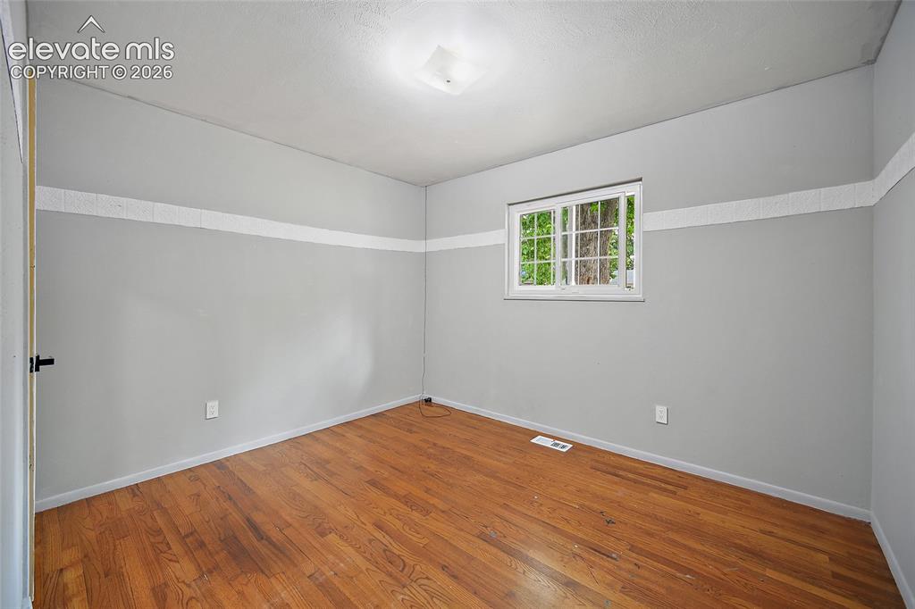 Image 17 of 39: Room with wood-finish flooring, light gray walls, and a white trim accent