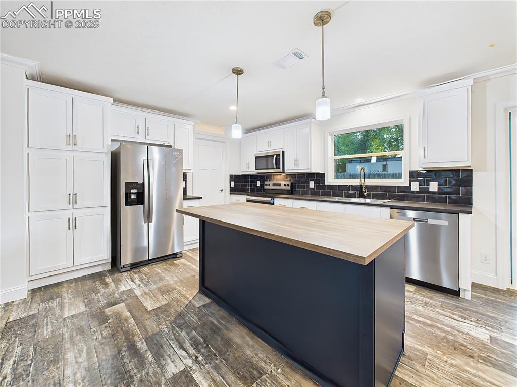 Image 12 of 50: Large center island with pendant lighting and breakfast bar seating.