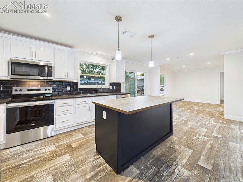 Image 13 of 50: Gourmet kitchen with white cabinetry, sleek black subway tile backsplash, a