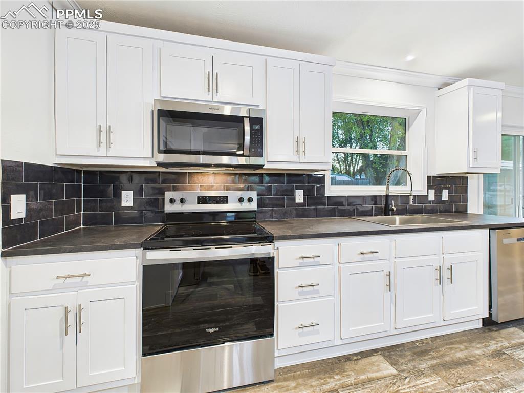 Image 14 of 50: Crisp white cabinetry paired with a bold black subway tile backsplash and c
