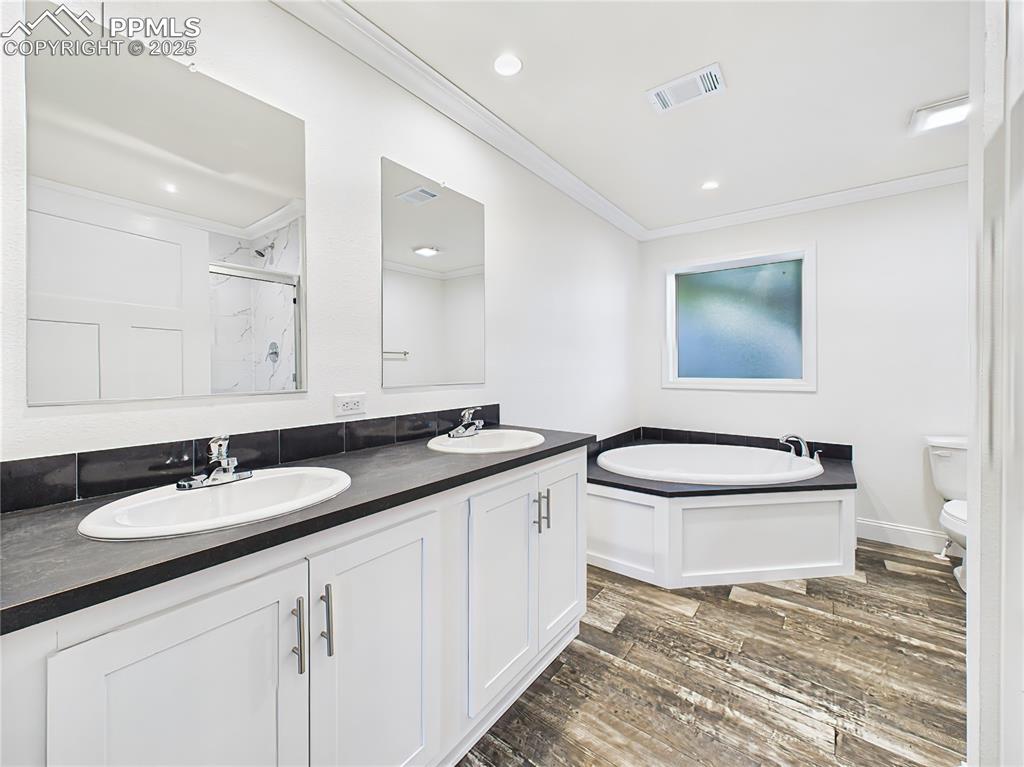 Image 35 of 50: Relaxing corner soaking tub and separate walk-in shower with marble-look ti