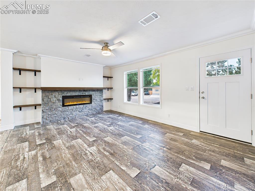 Image 4 of 50: Striking floor-to-ceiling stone electric fireplace with wood mantel and bui