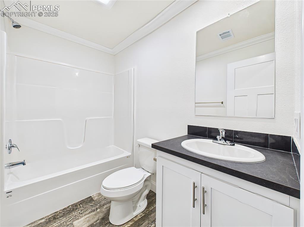 Image 44 of 50: Full bath featuring white vanity with storage, modern black countertops, an
