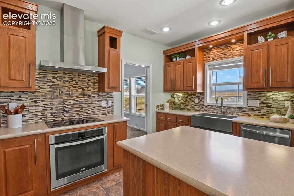 Image 8 of 44: The kitchen features a hood vent, cook top, and pot filler. 