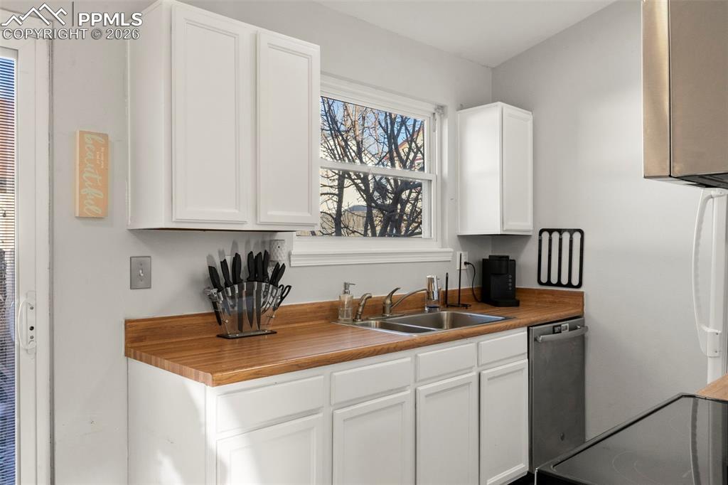 Image 11 of 29: Kitchen with white cabinetry, stainless steel dishwasher, electric range, a
