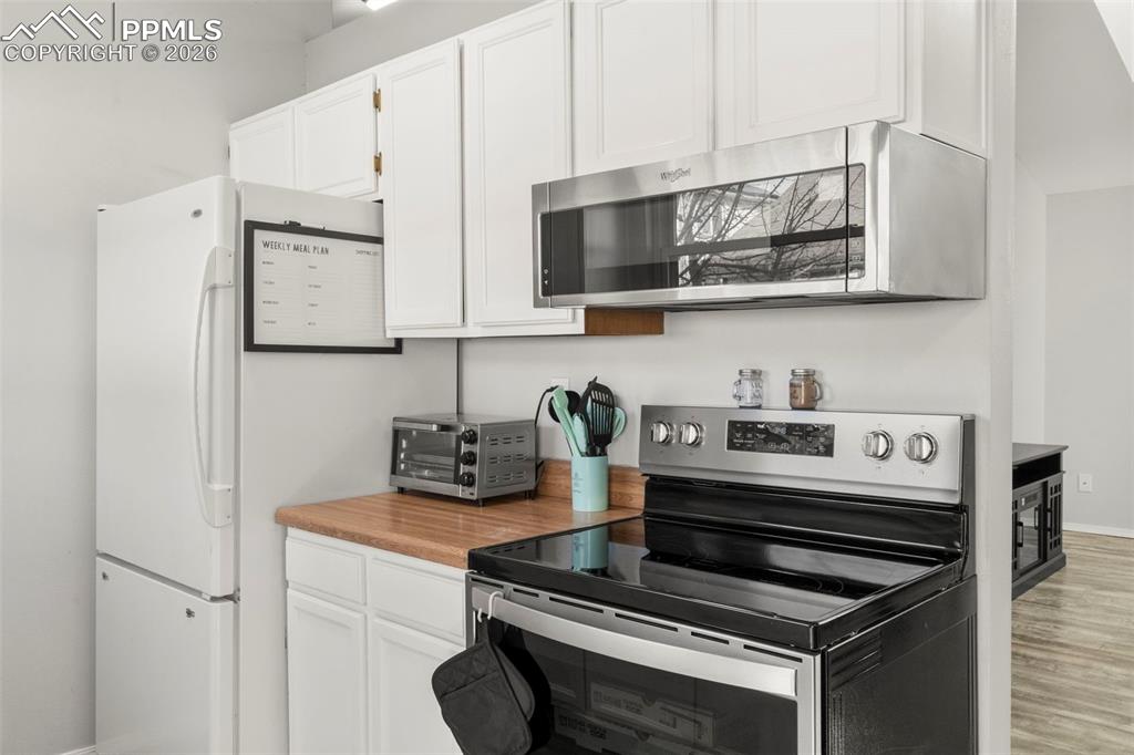 Image 12 of 29: Kitchen featuring stainless steel appliances, white cabinets, light counter