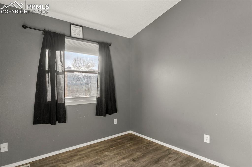Image 14 of 29: Unfurnished room featuring dark wood-type flooring and lofted ceiling