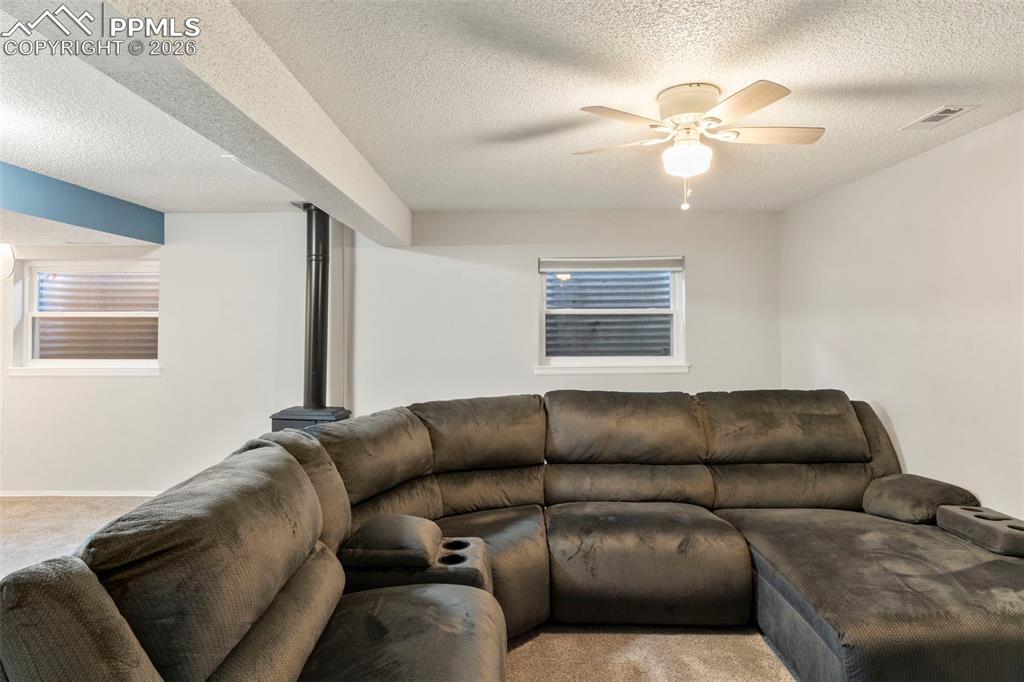 Image 18 of 29: Living area featuring light carpet, a textured ceiling, and ceiling fan