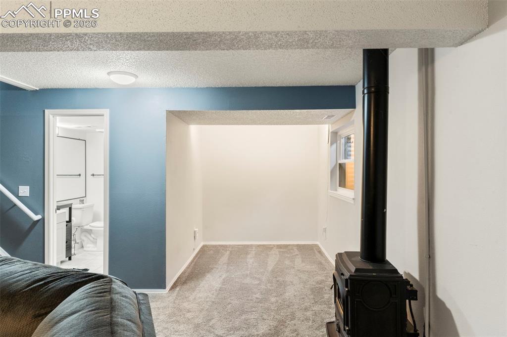 Image 19 of 29: Carpeted living room featuring a textured ceiling and a wood stove