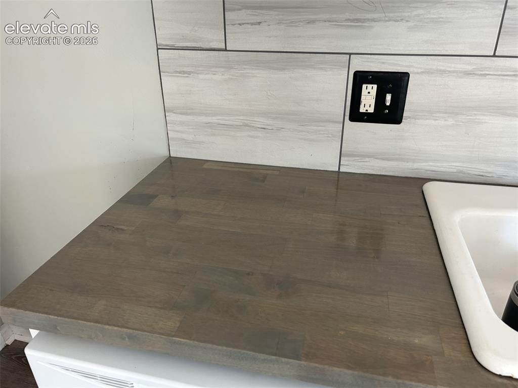 Image 23 of 45: Wood-finish countertop with an integrated white sink and a tiled backsplash