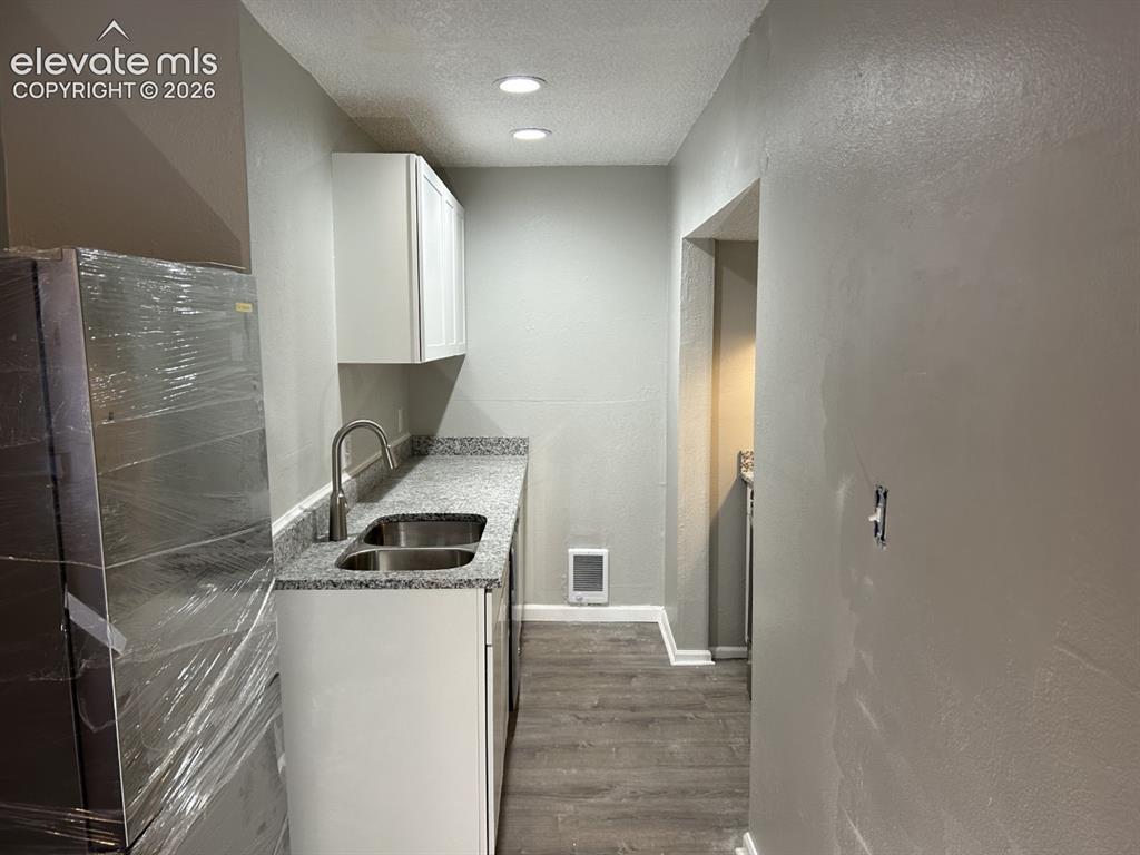 Image 3 of 45: Cottage kitchen lighting, white upper cabinetry, stainless steel sink, wood