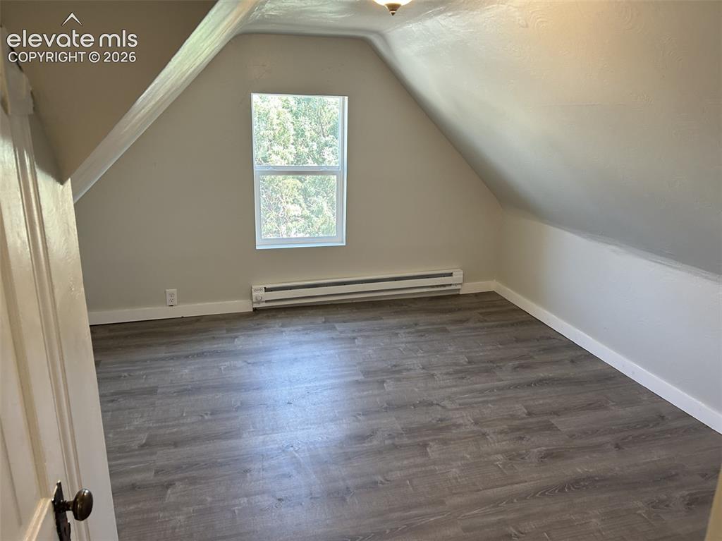 Image 41 of 45: Attic room featuring wood-finish flooring, an angled ceiling, a single wind