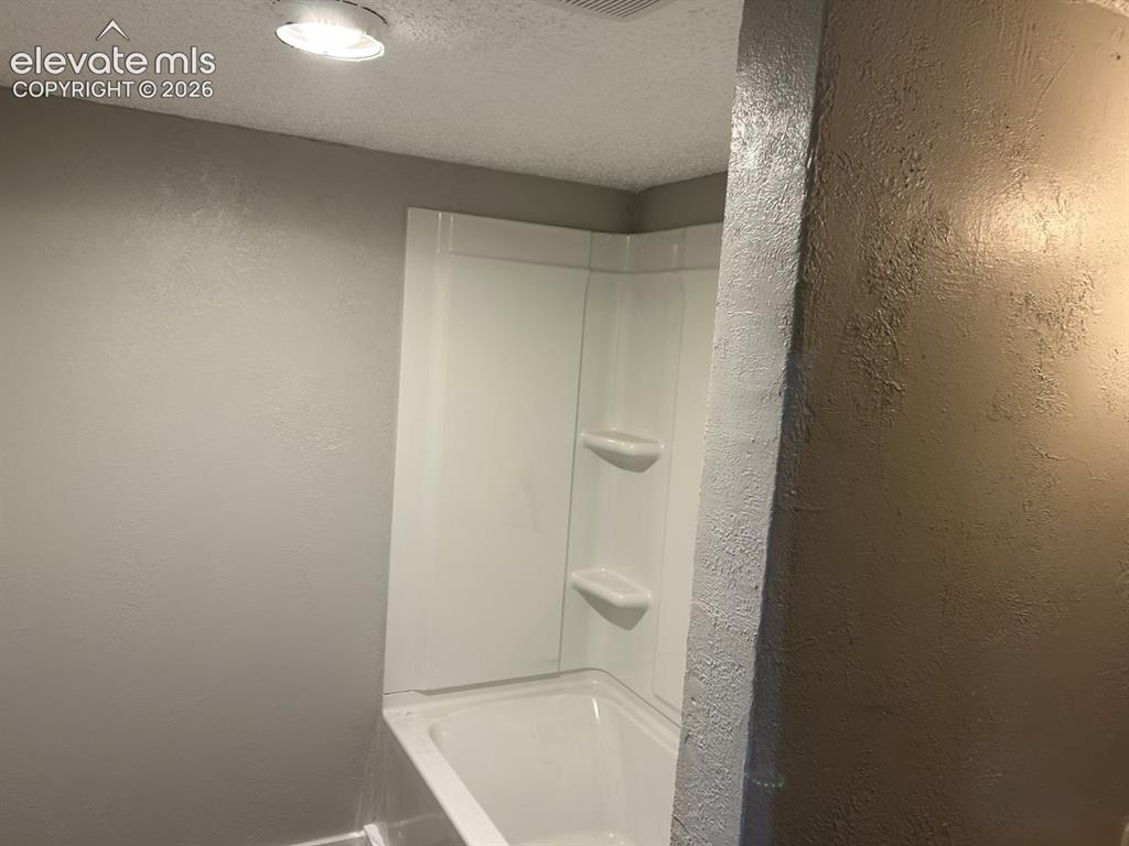 Image 6 of 45: Bathtub with integrated shelving and overhead lighting
