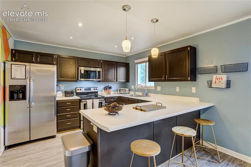 Image 10 of 40: Kitchen featuring dark wood cabinetry, white countertops, stainless steel a