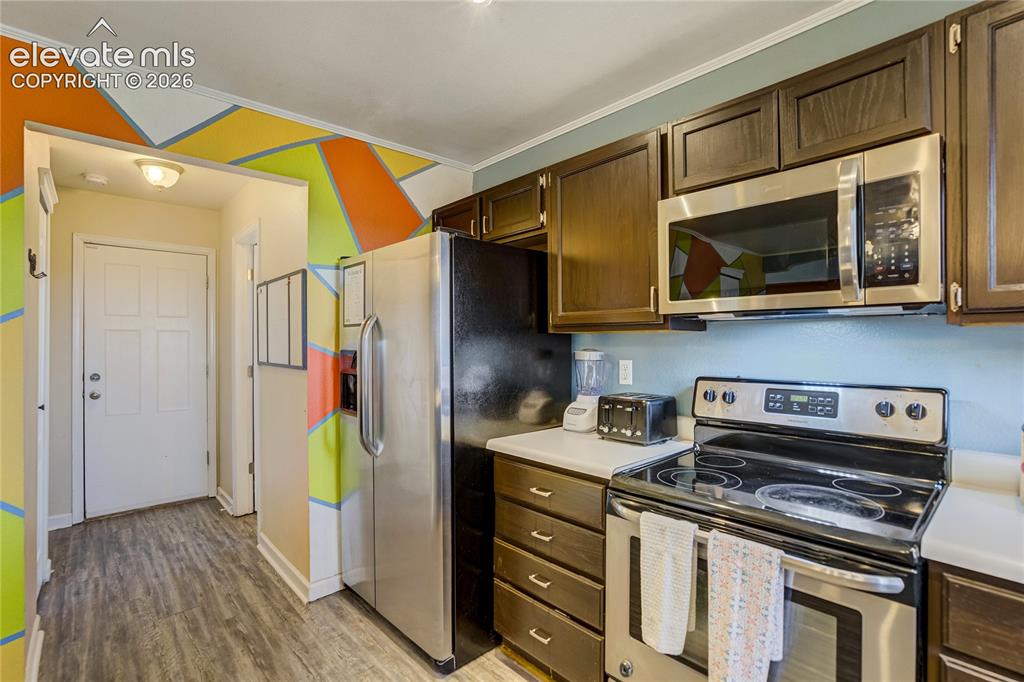 Image 13 of 40: Kitchen area featuring dark wood-finish cabinetry, stainless steel applianc