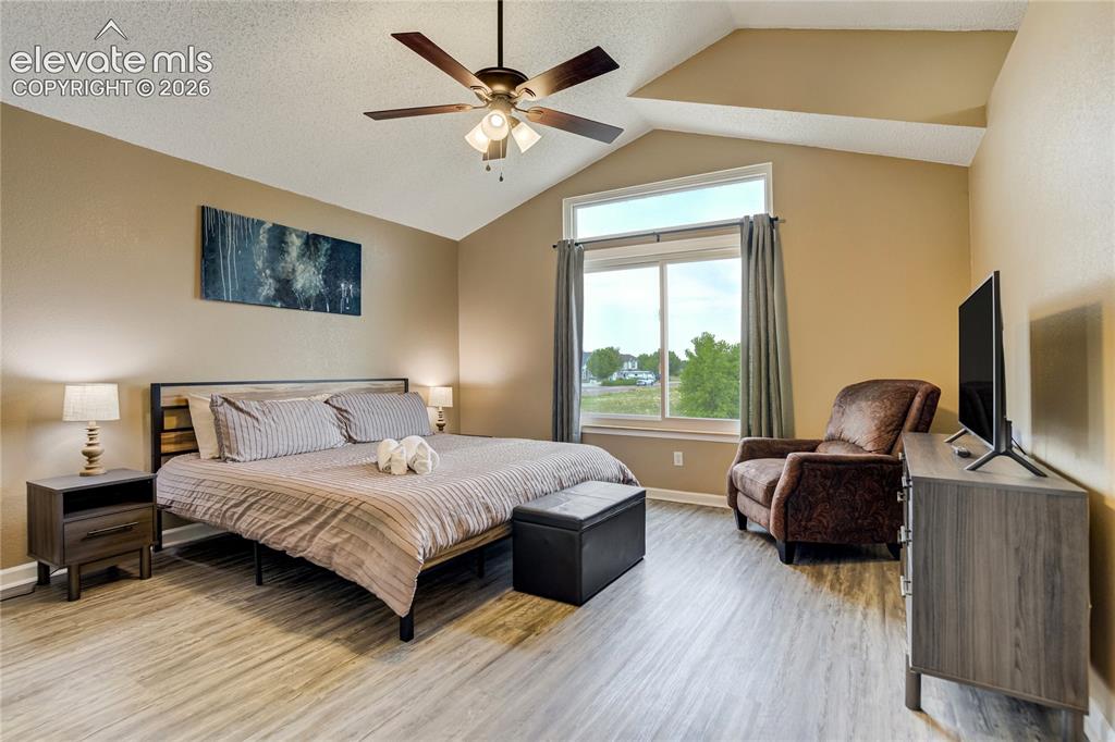 Image 16 of 40: Spacious room featuring vaulted ceilings, wood-finish flooring, a large win