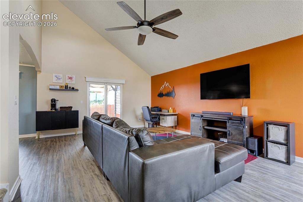 Image 2 of 40: Spacious living area featuring wood-finish flooring, vaulted ceilings, and