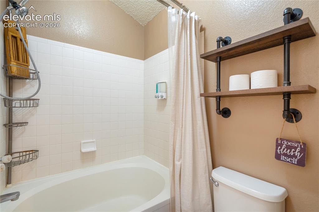 Image 22 of 40: Bathroom featuring a standard bathtub with white tile surround, a shower cu