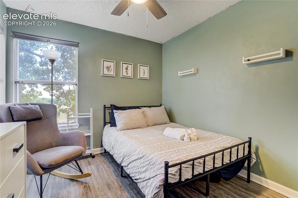 Image 27 of 40: Bedroom featuring a window with exterior tree views, wood-finish flooring,