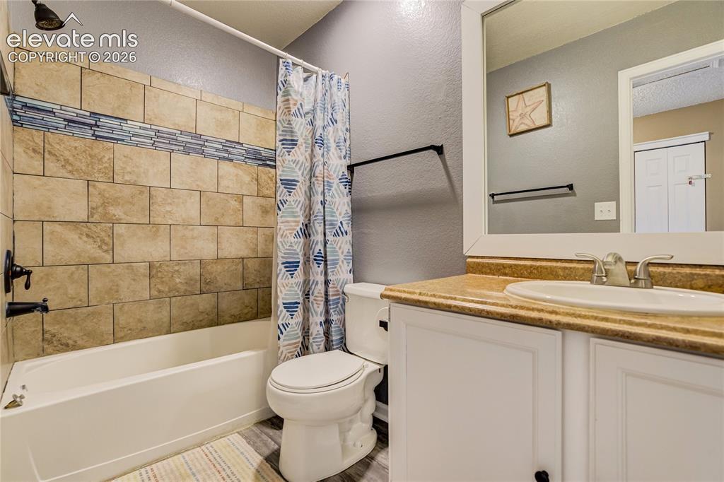 Image 29 of 40: Bathroom featuring a white vanity with a tan countertop, a white drop-in si
