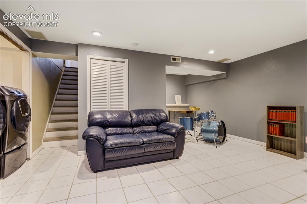 Image 32 of 40: Spacious finished basement with light-colored tile flooring, overhead reces