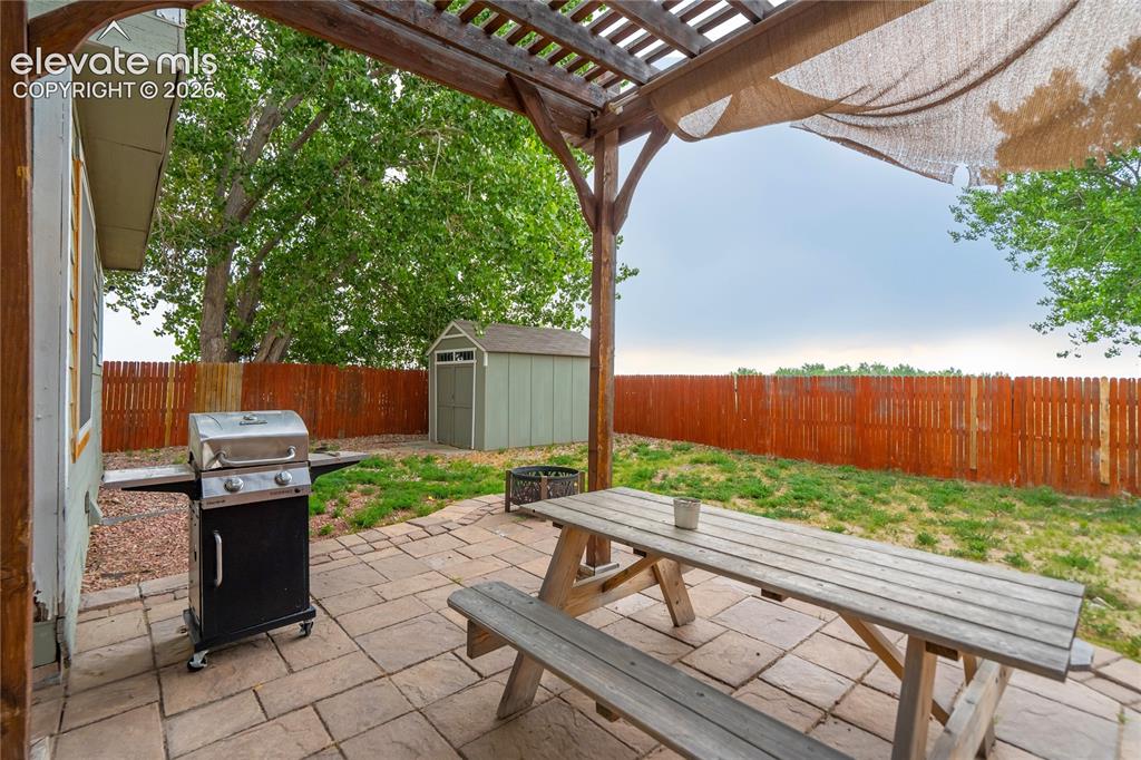 Image 38 of 40: Outdoor patio featuring a wood pergola with shade fabric, paver flooring, a