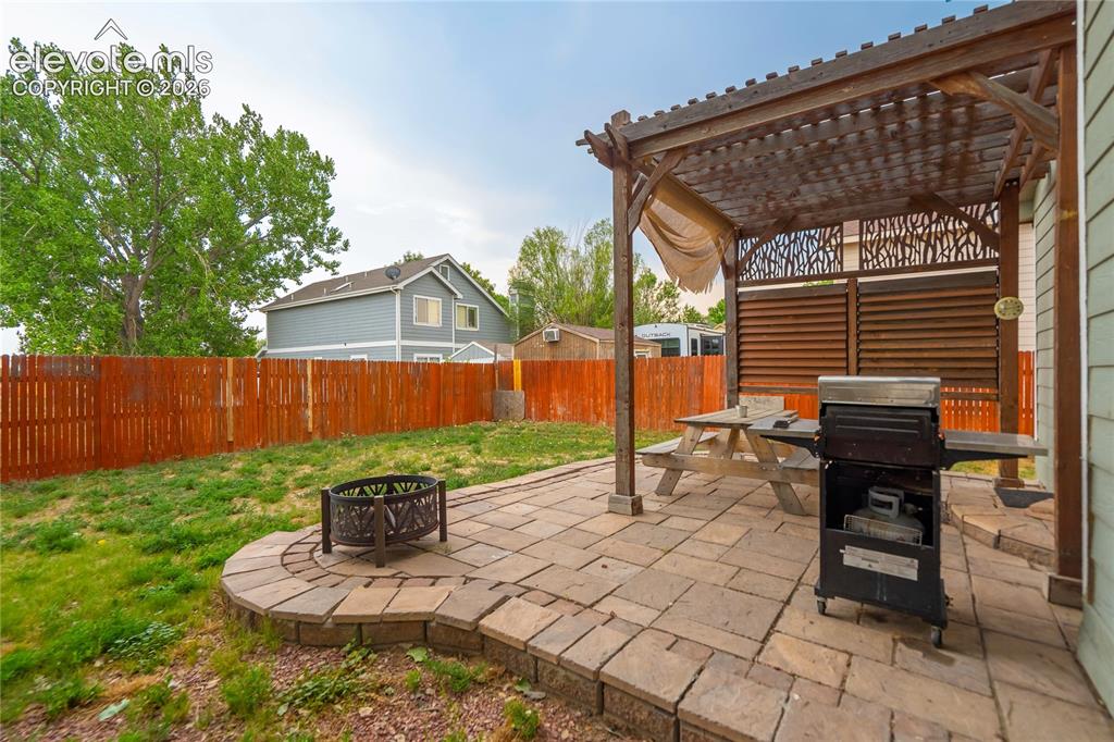 Image 39 of 40: Paver patio featuring a wood pergola with patterned privacy screen, a raise