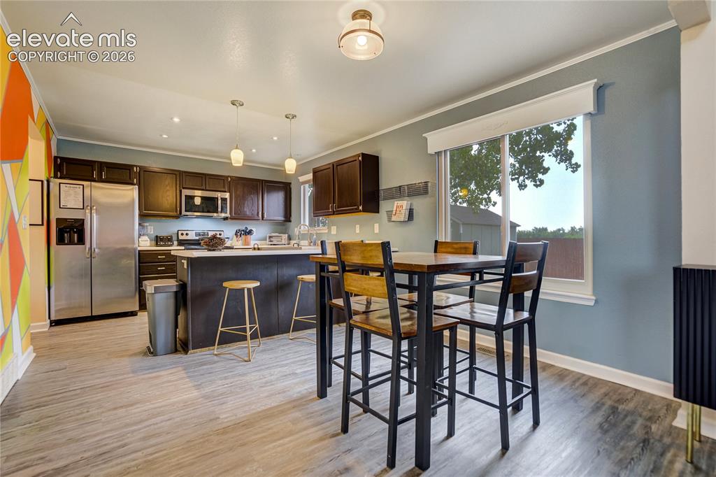 Image 6 of 40: Open-concept kitchen featuring dark wood cabinetry, stainless steel applian