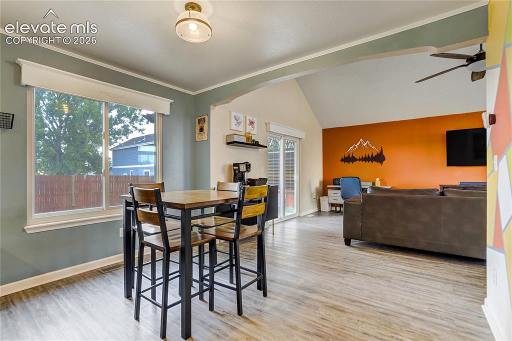Image 7 of 40: Open-concept living area featuring wood-finish flooring, a vaulted ceiling,