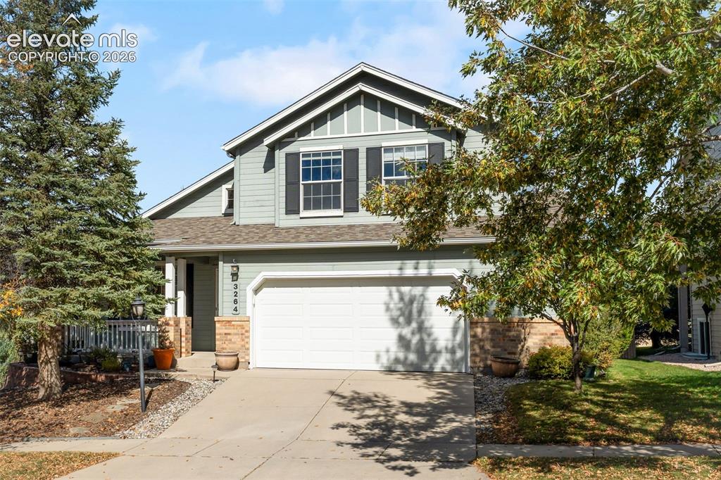 Caption: Two-story exterior featuring sage-colored horizontal lap siding, stone veneer accents, a double-widt