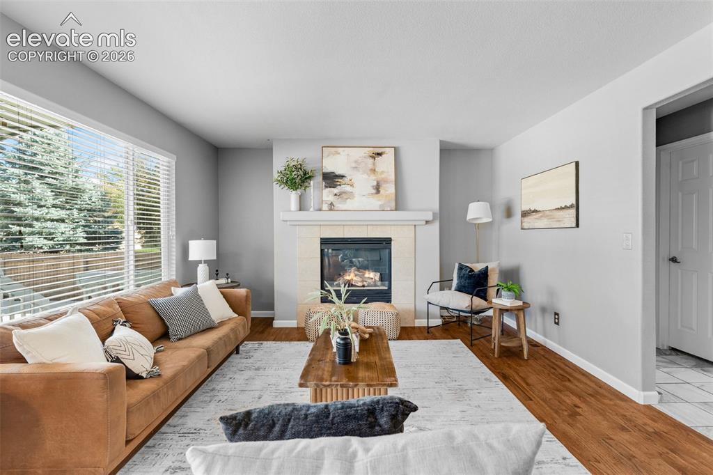 Image 11 of 36: Living room featuring wood-finish flooring, a fireplace with a neutral-tone