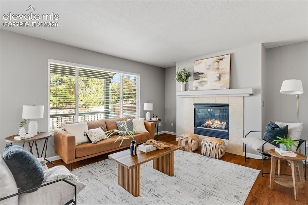 Image 12 of 36: Living area featuring large windows with horizontal blinds, wood-finish flo
