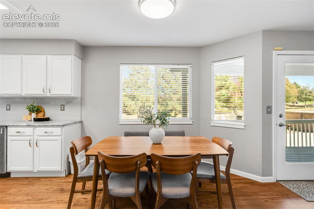 Image 14 of 36: Kitchen area featuring white shaker-style cabinetry, stone-finish counterto