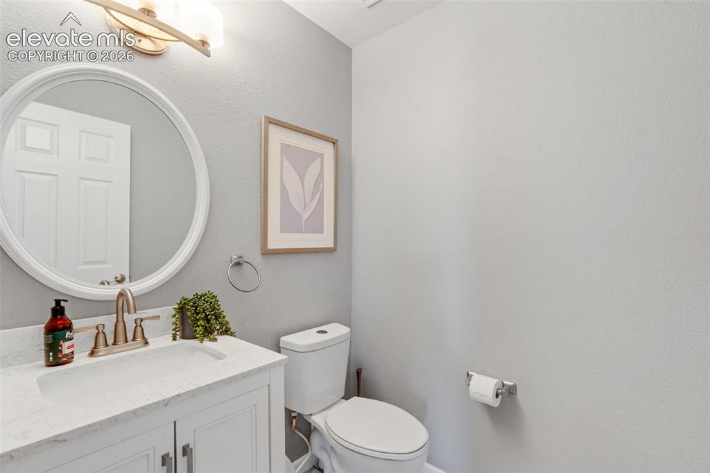 Image 16 of 36: White vanity featuring a stone-look countertop, integrated basin, and warm-