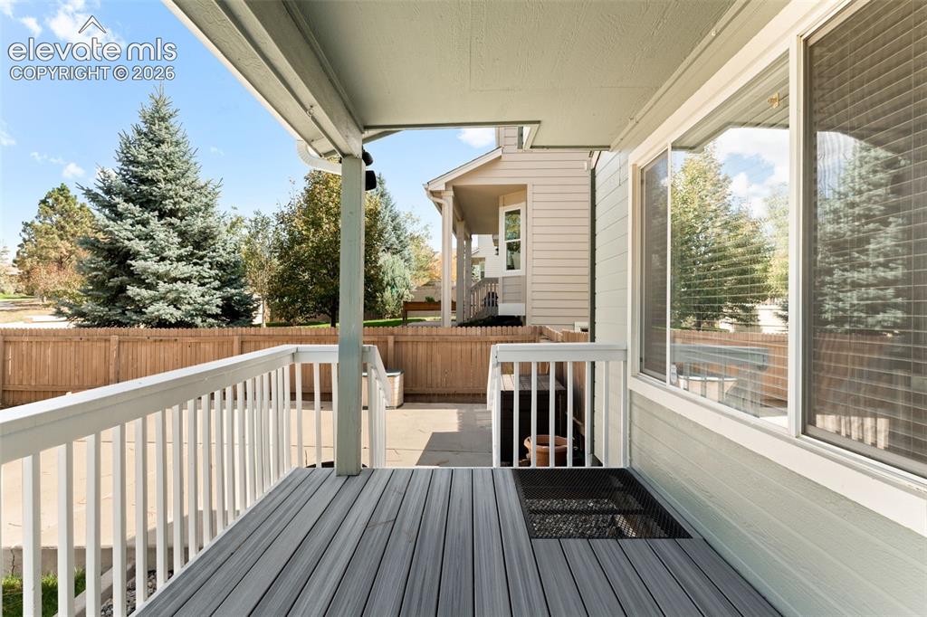 Image 33 of 36: Covered deck featuring gray wood-finish planks, white baluster railings, an
