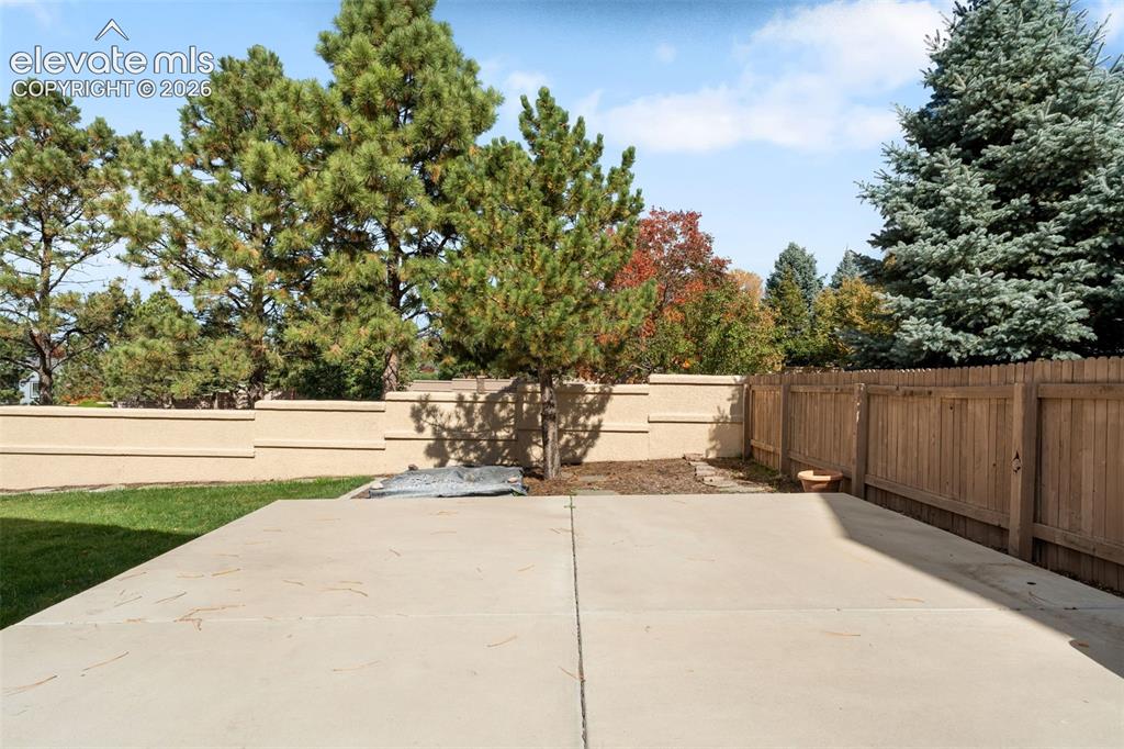 Image 36 of 36: Concrete patio featuring a perimeter of wood fencing and stucco wall bounda