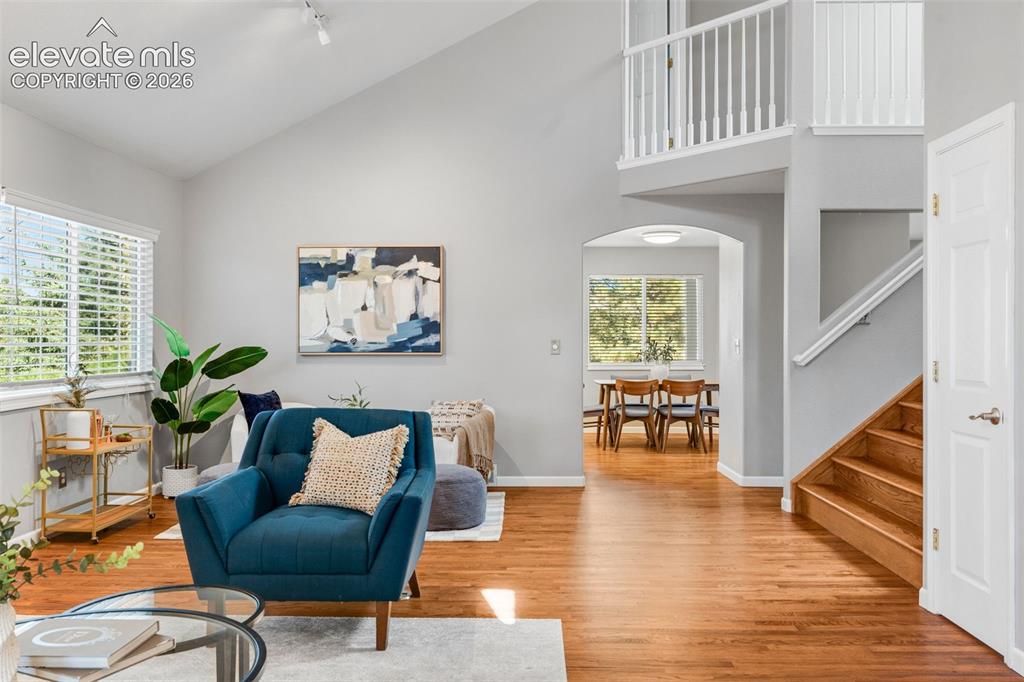 Image 6 of 36: Vaulted ceilings, wood-finish flooring, an arched entryway, and a staircase
