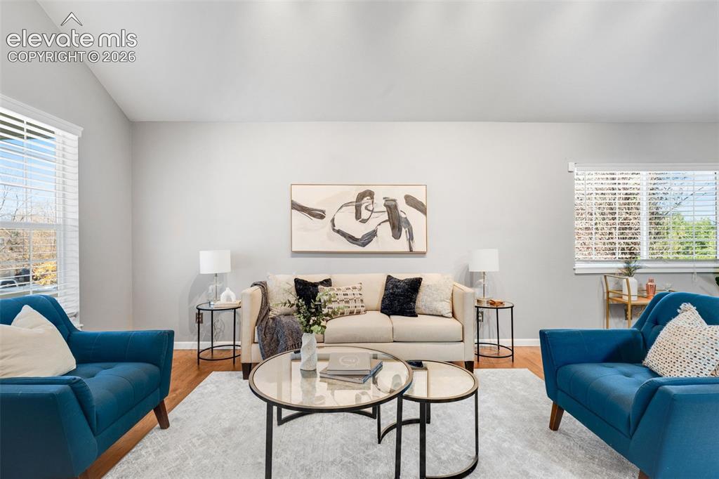 Image 7 of 36: Vaulted ceiling, wood-finish flooring, and multi-pane windows with horizont