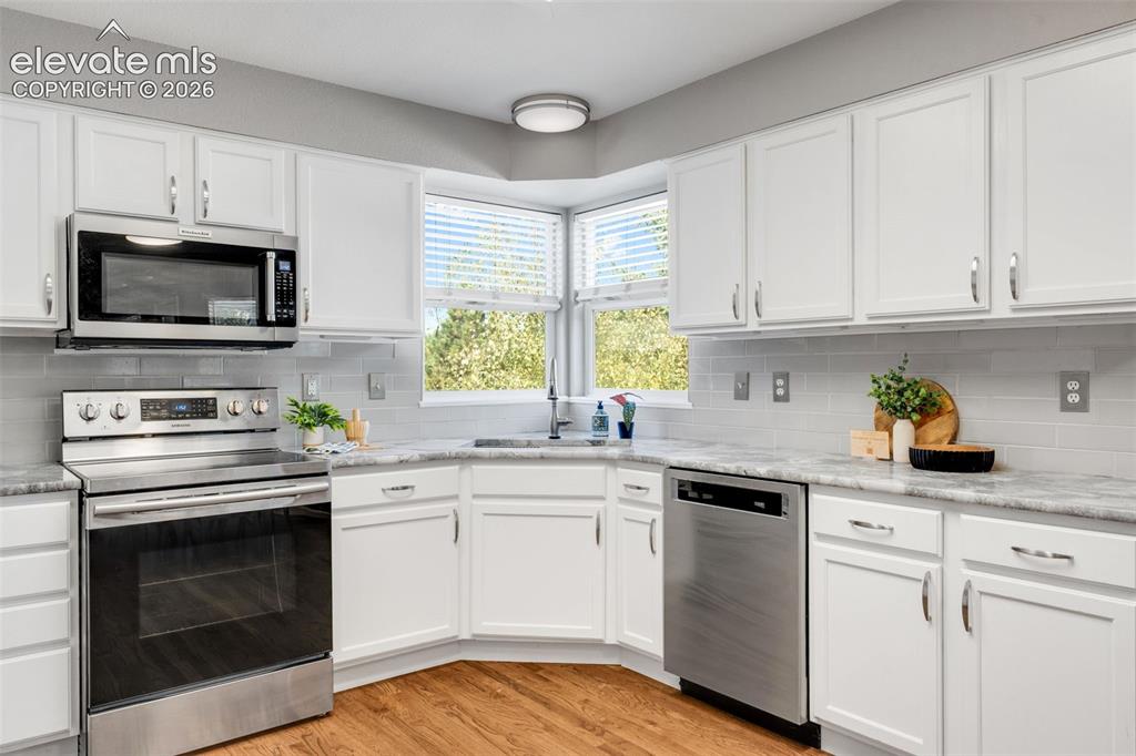 Image 9 of 36: Kitchen featuring white cabinetry, stone-finish countertops, stainless stee