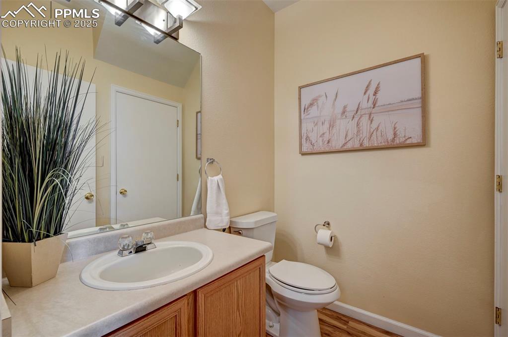 Image 13 of 26: Bathroom with toilet, vanity, baseboards, and wood finished floors