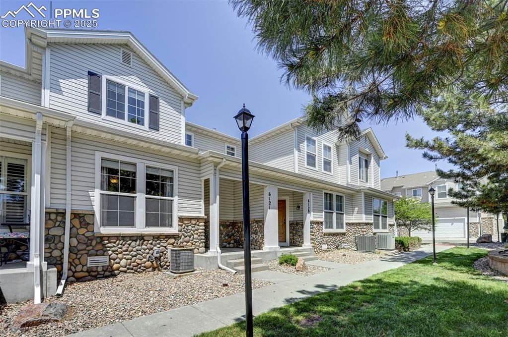 Image 2 of 26: View of front facade featuring stone siding, a porch, and cooling unit