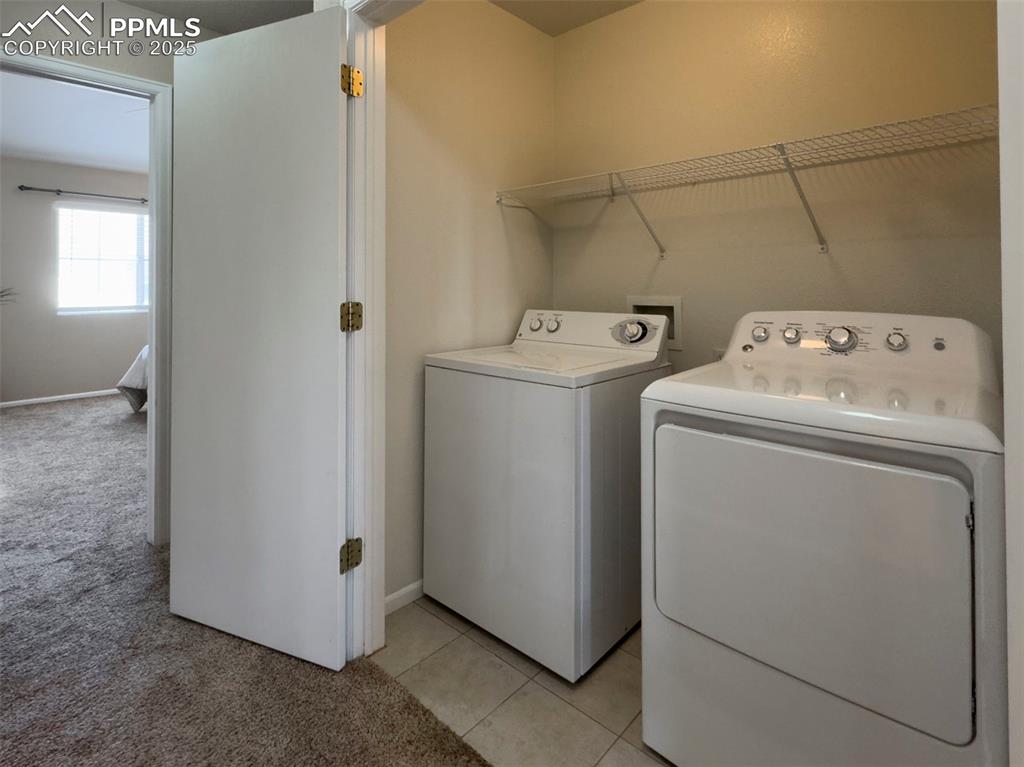 Image 21 of 26: Laundry area with washing machine and clothes dryer, light carpet, and base