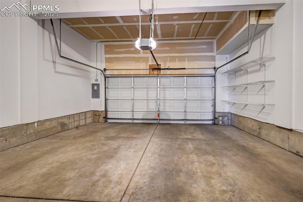Image 23 of 26: Garage with a garage door opener and electric panel
