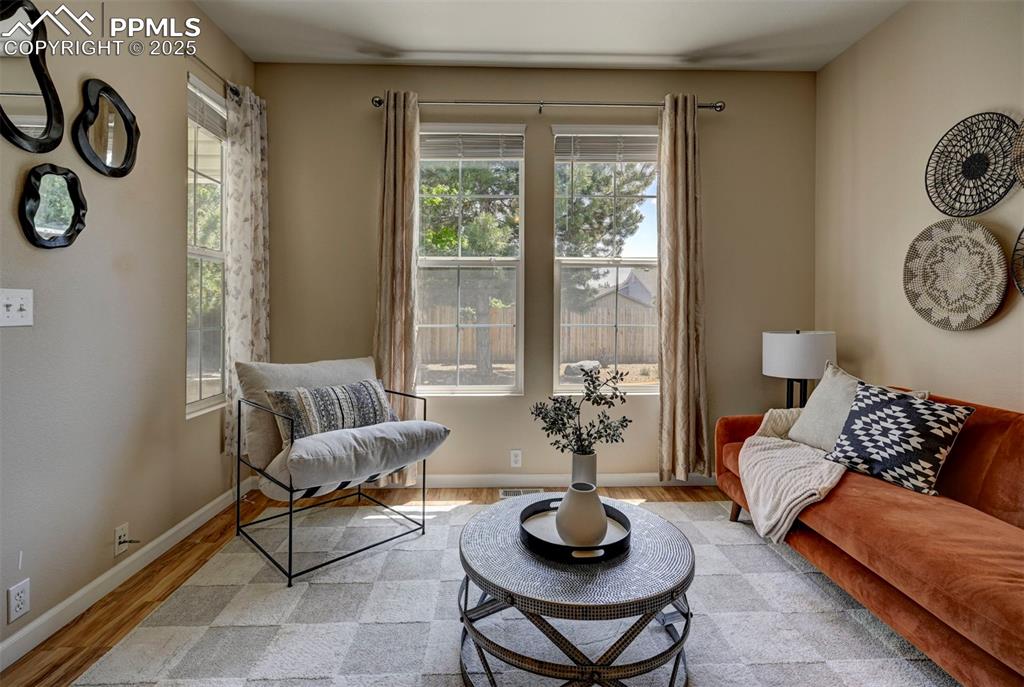 Image 7 of 26: Sitting room with plenty of natural light, wood finished floors, and basebo