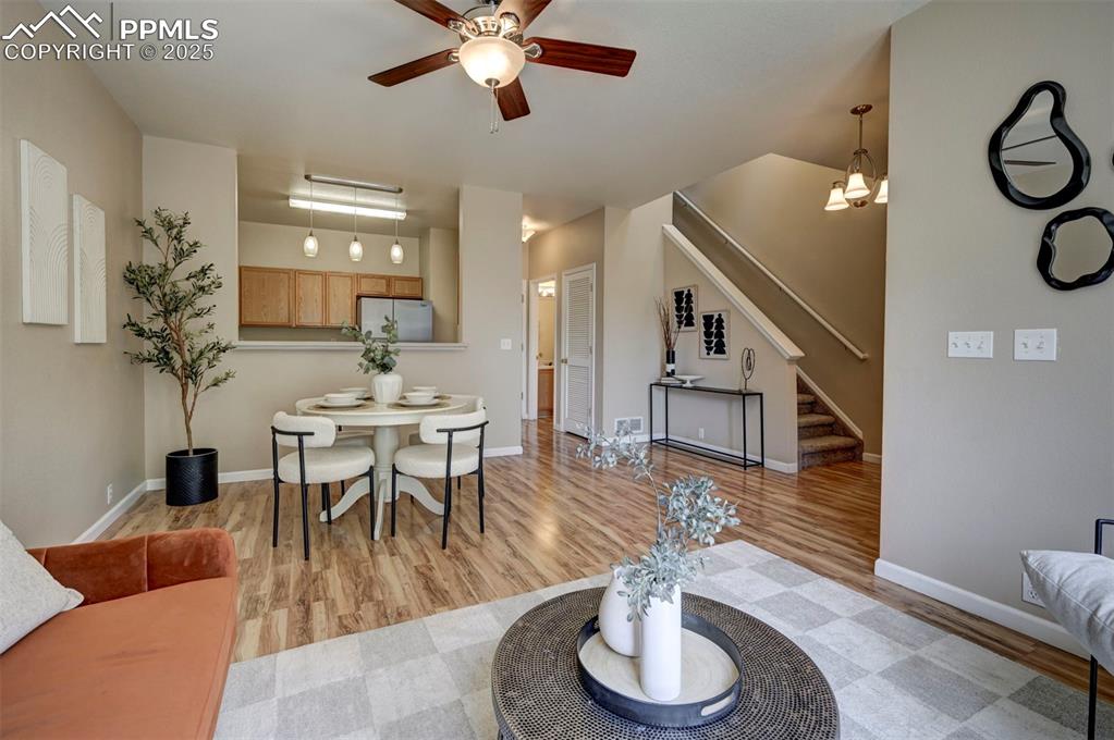 Image 8 of 26: Living area featuring a ceiling fan, stairway, light wood-type flooring, an