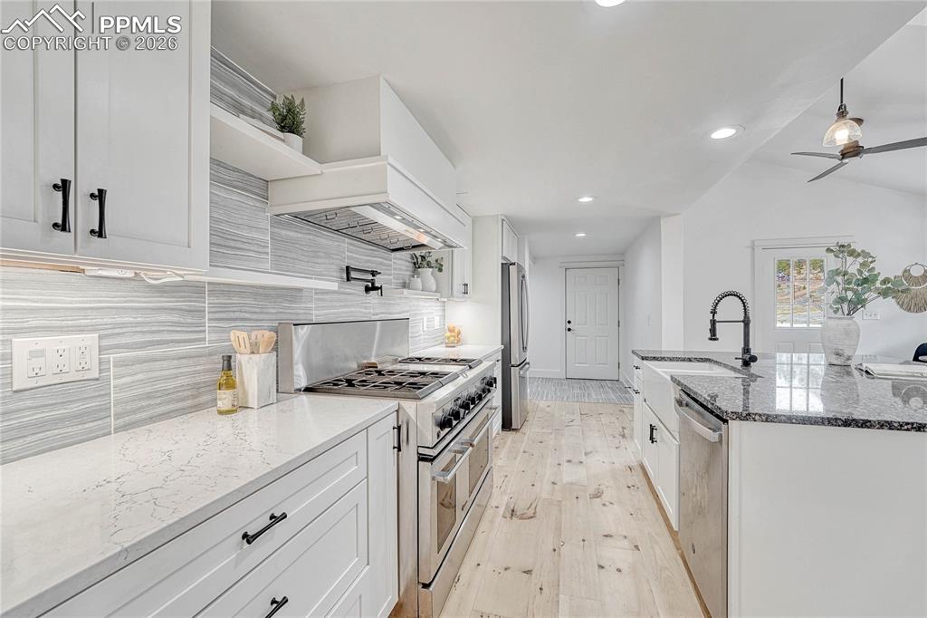 Image 14 of 45: Kitchen, wood floors, sink, stainless steel appliances, custom range hood,